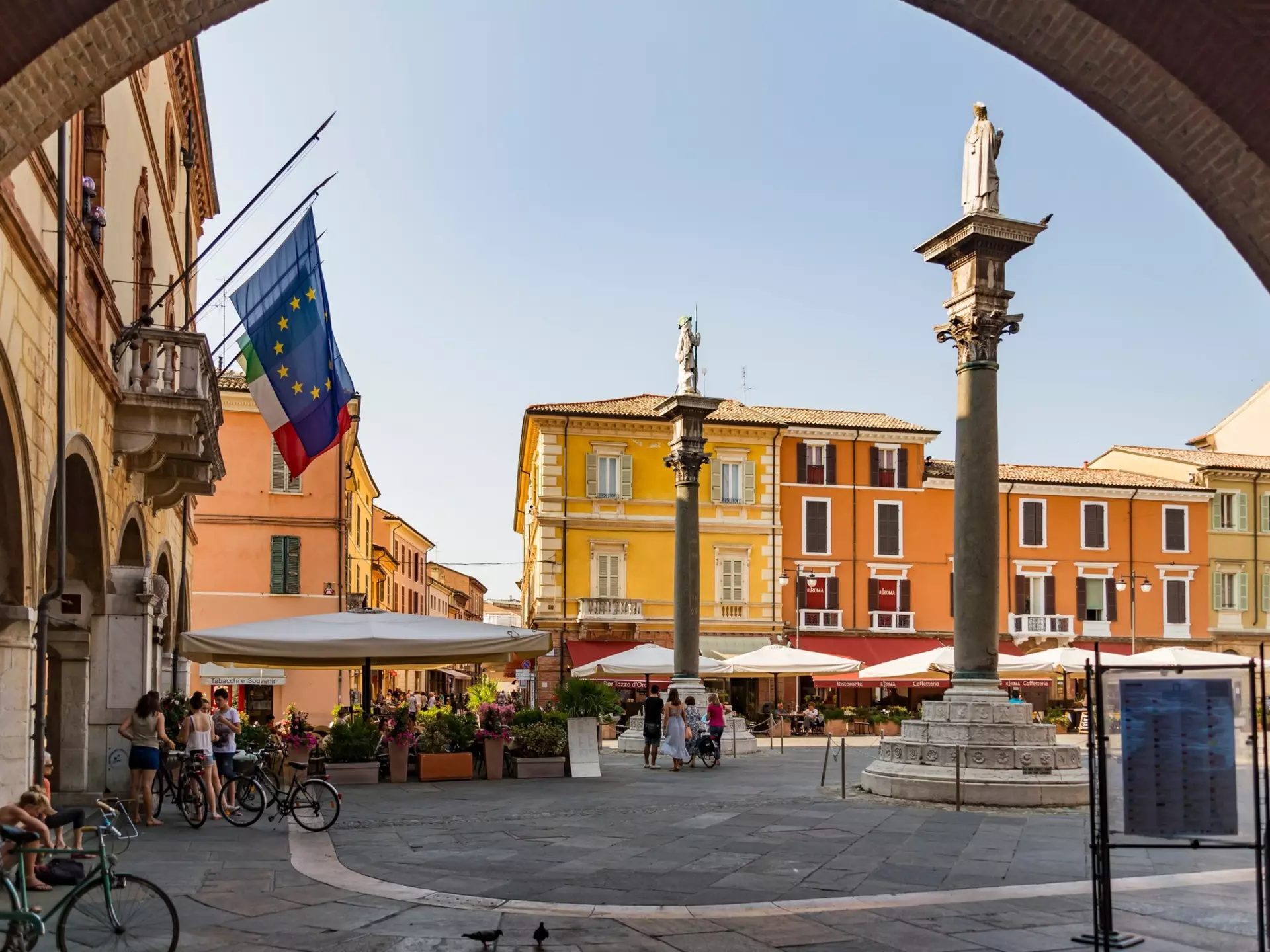 A city square where people are relaxing on a restaurant terrace