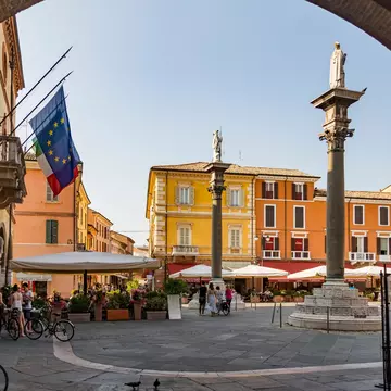 A city square where people are relaxing on a restaurant terrace