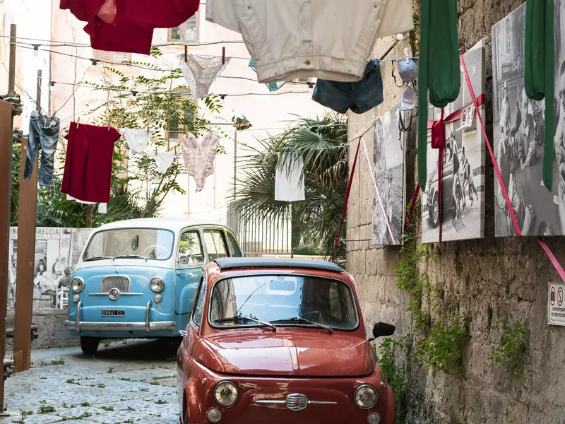 Two cars and clothes at Gallery Celentano + Open air gallery, Sorrento, Italy. July 2025.