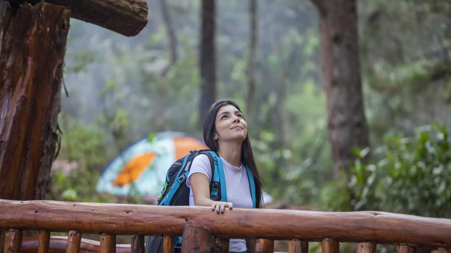 A woman walks over a wooden bridge in Parque Arví, Medellín