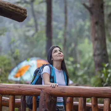 A woman walks over a wooden bridge in Parque Arví, Medellín