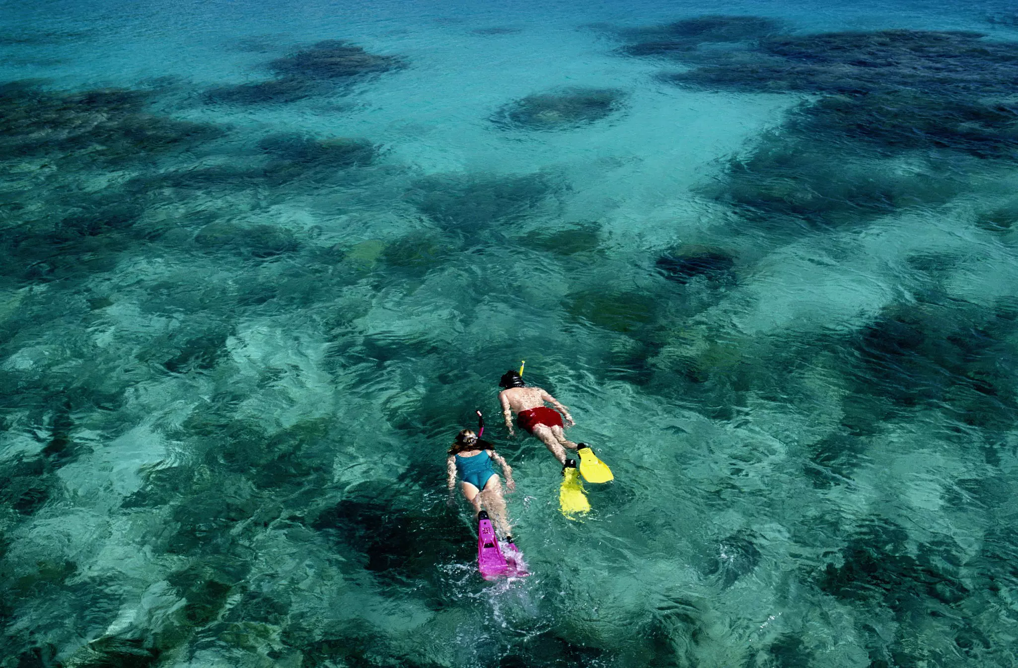 Aerial shot of two snorkellers exploring a reef.