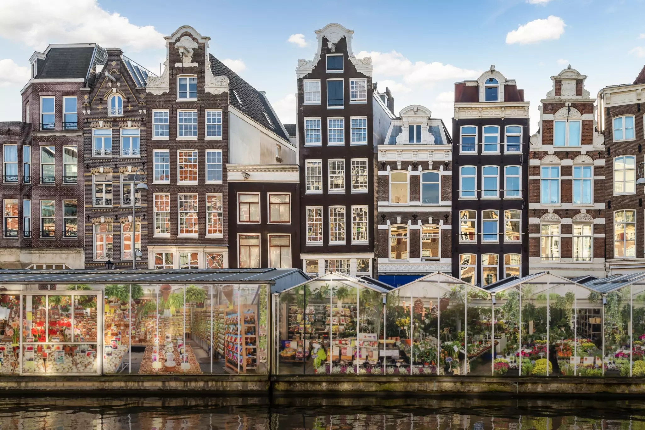 Tall narrow houses line a canal near a flower market.