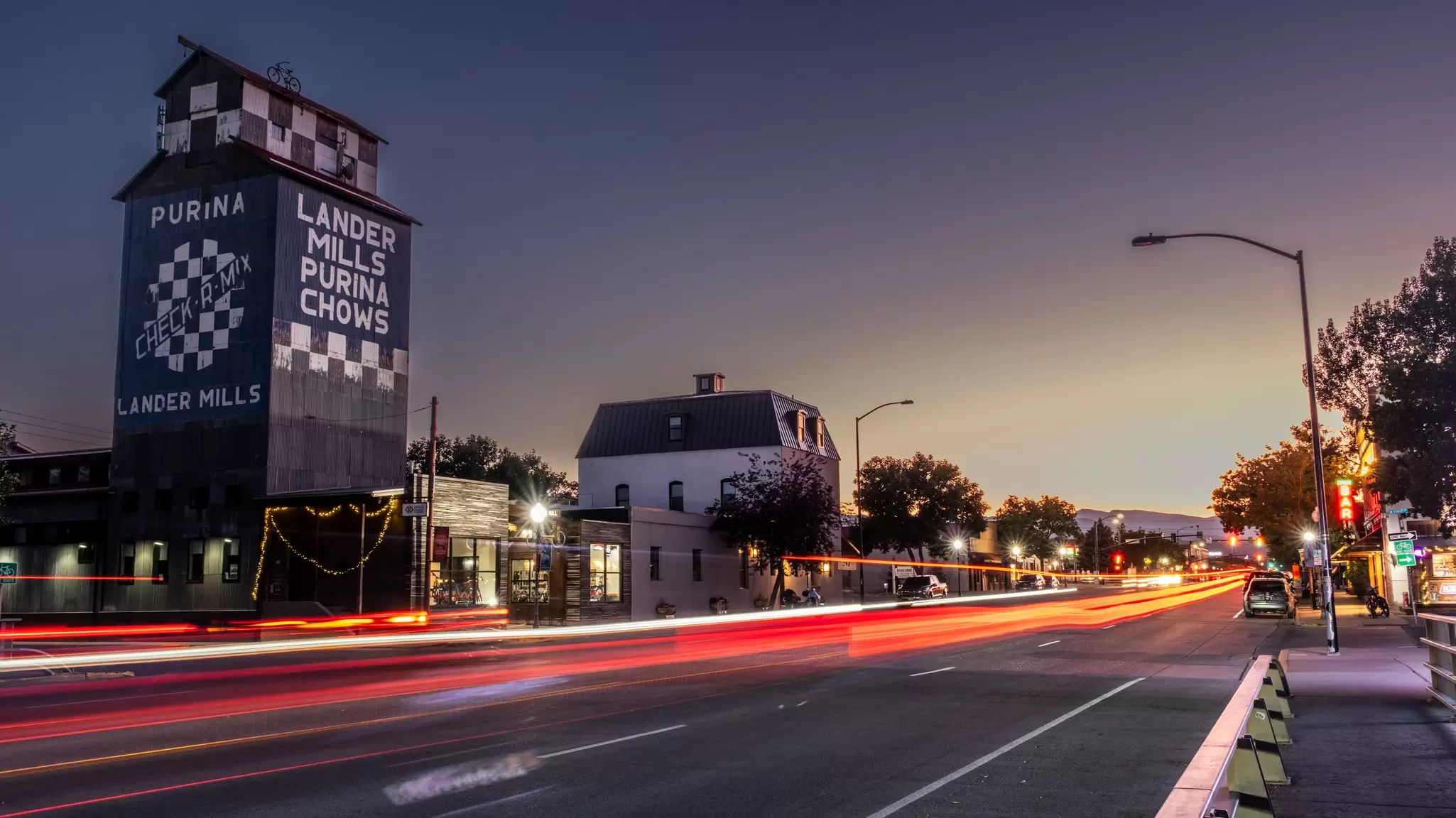 Evening falls on Main St in Lander, Wyoming, with the Purina Chows mill building lit by a sunset. 