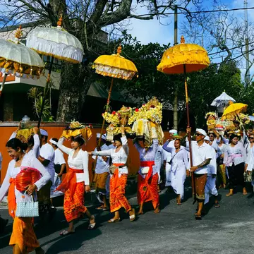 Islanders with colorful clothing and umbrellas take part in a Melasti procession near Jimbaran in Bali during Nyepi. 