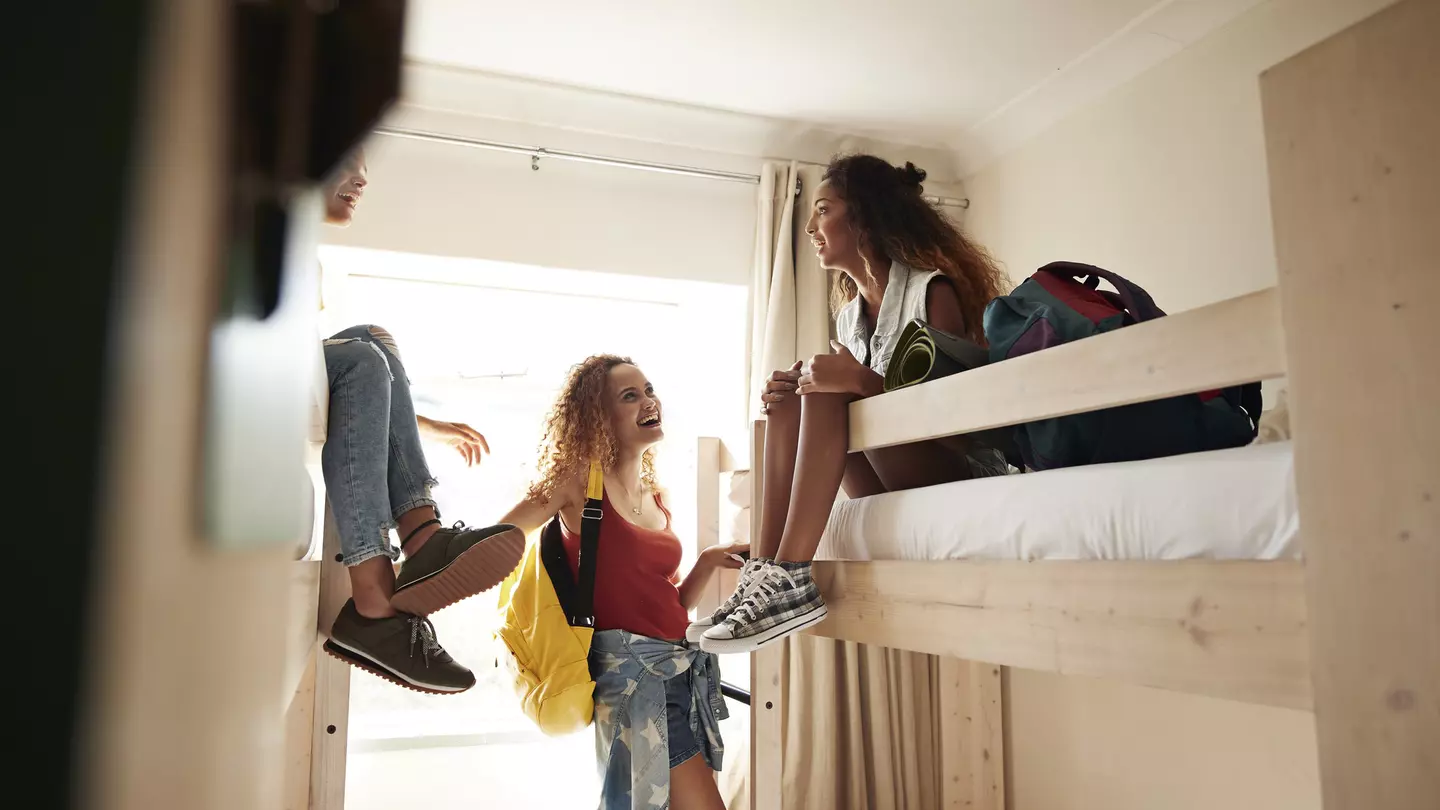 Young women arriving to room with bunk beds, at youth hostel