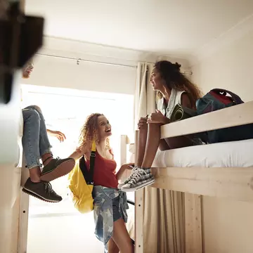 Young women arriving to room with bunk beds, at youth hostel