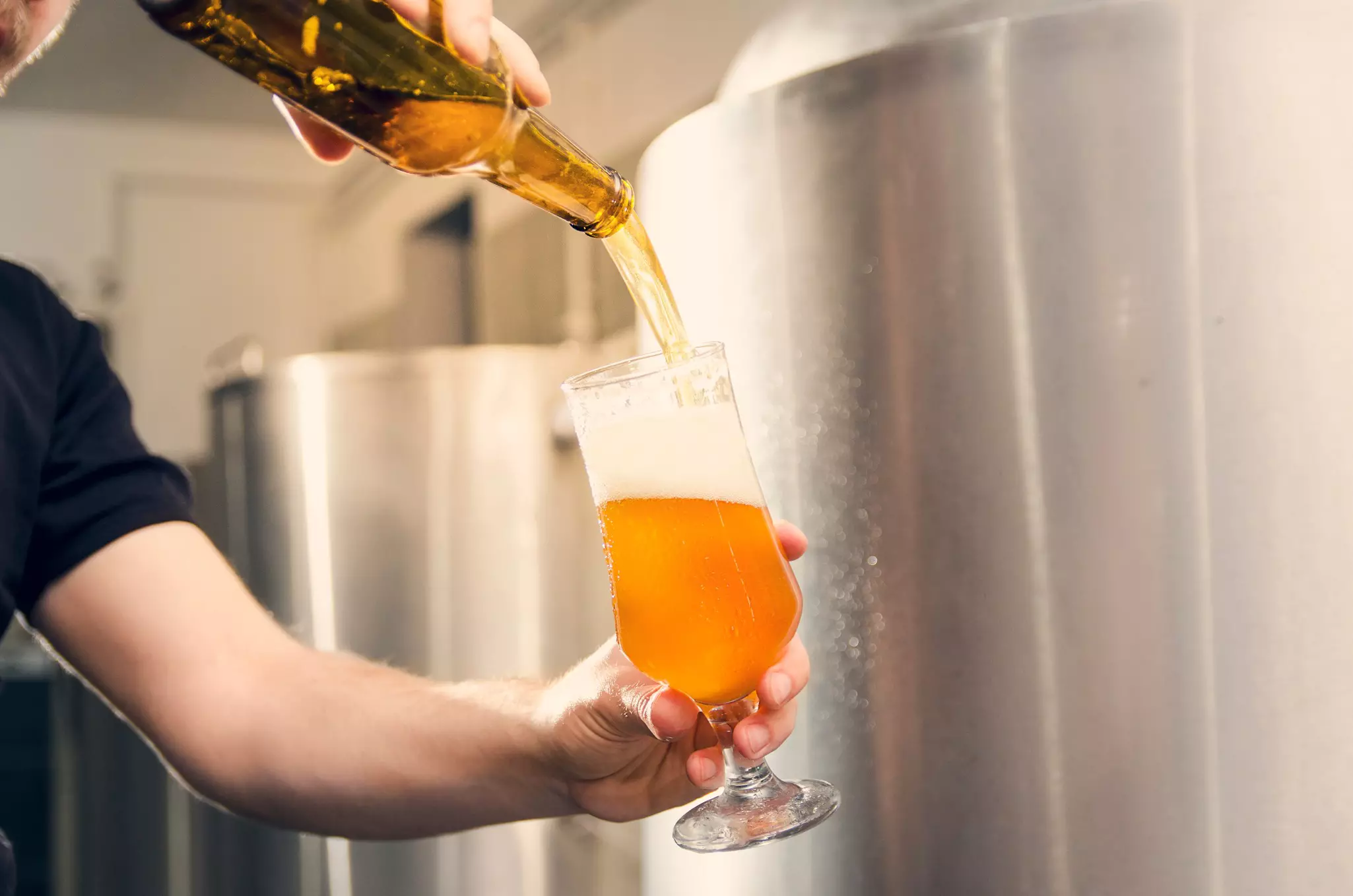 Closeup of man pouring beer from an unlabeled bottle into a glass