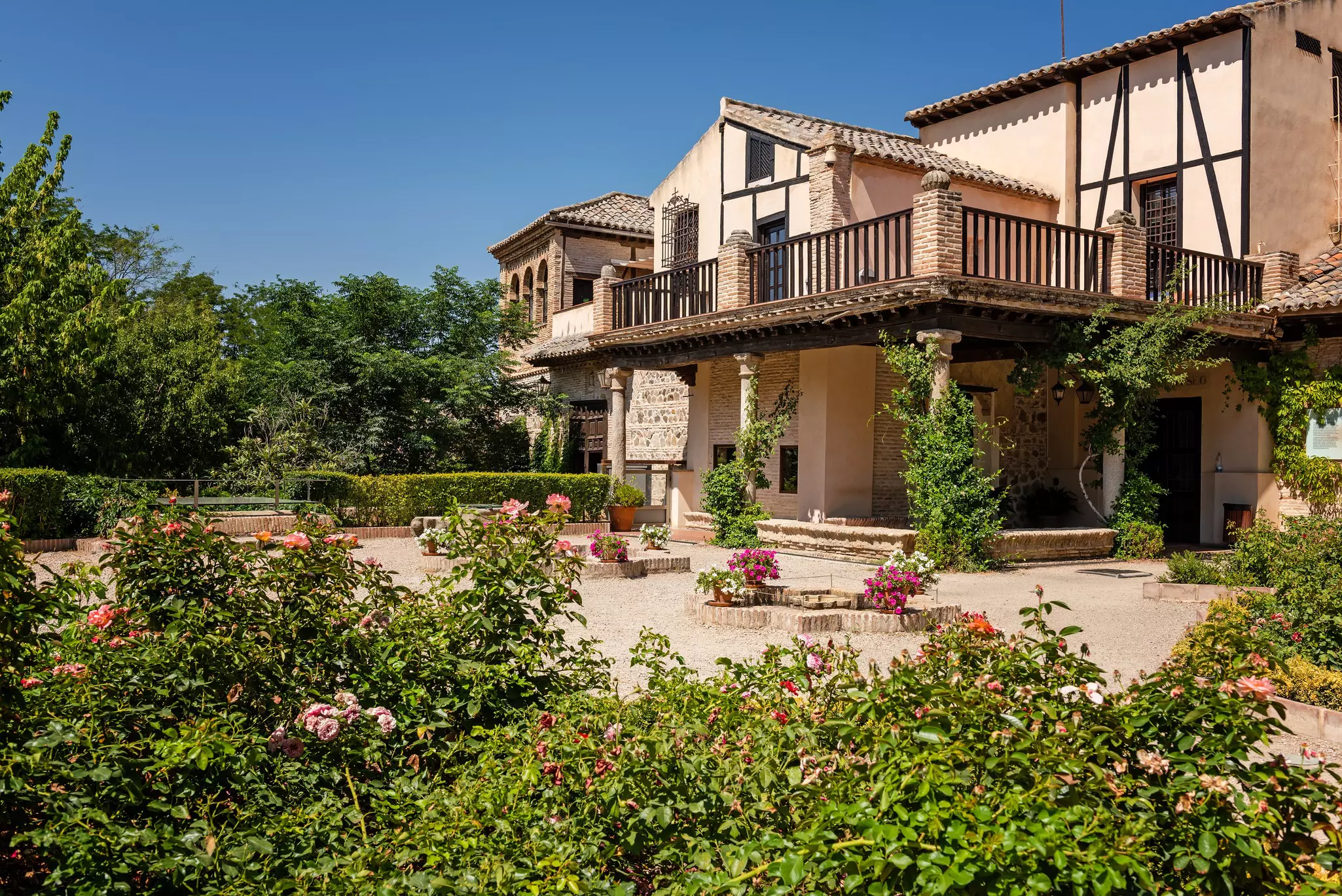 Exterior of a walled, stone house with plants and flowers displayed in its sunny courtyard