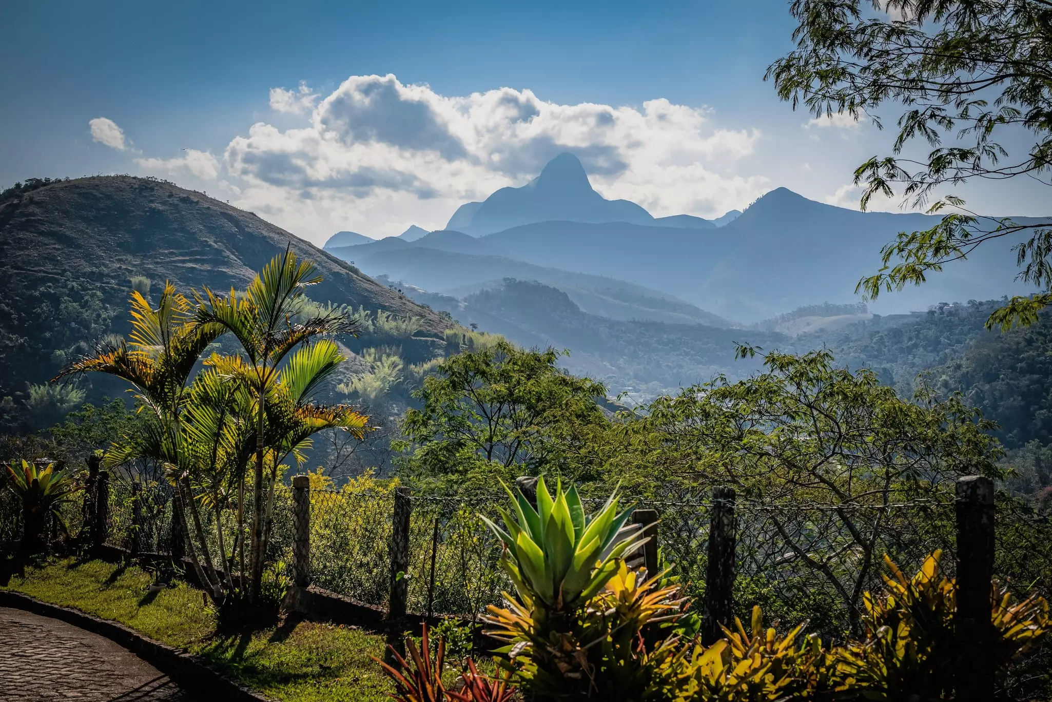 A mountain valley from an overlook in Brazil; mountains are silhouetted against clouds in the background.