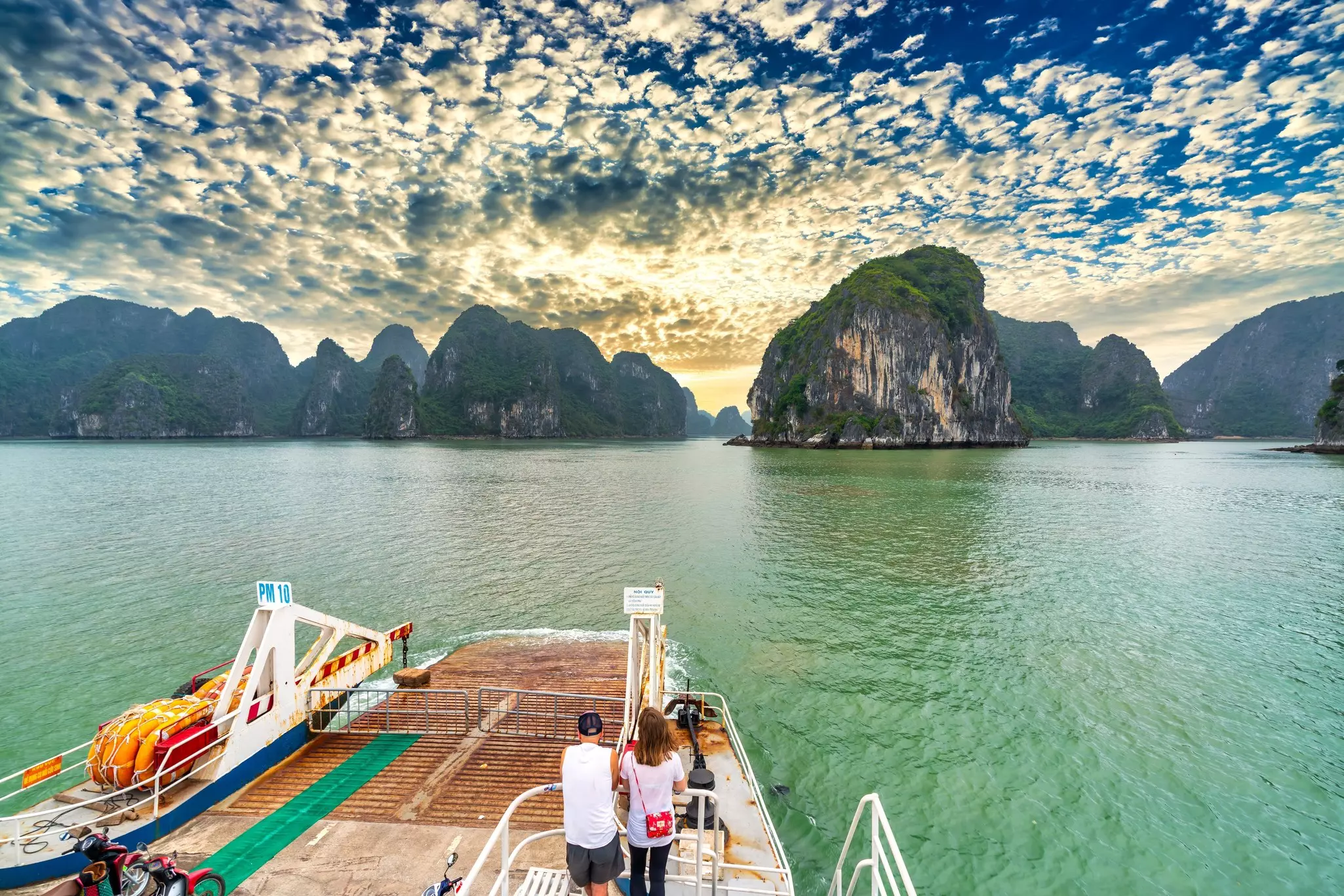 Two people on a boat in front of a large bay