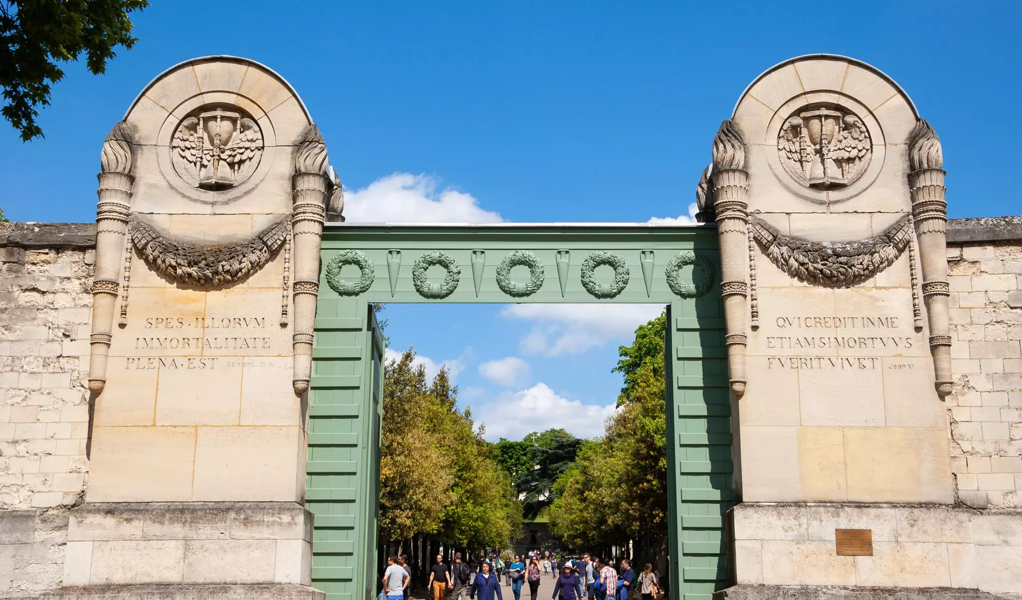 Pere Lachaise cemetery gate and visitors walking inside.