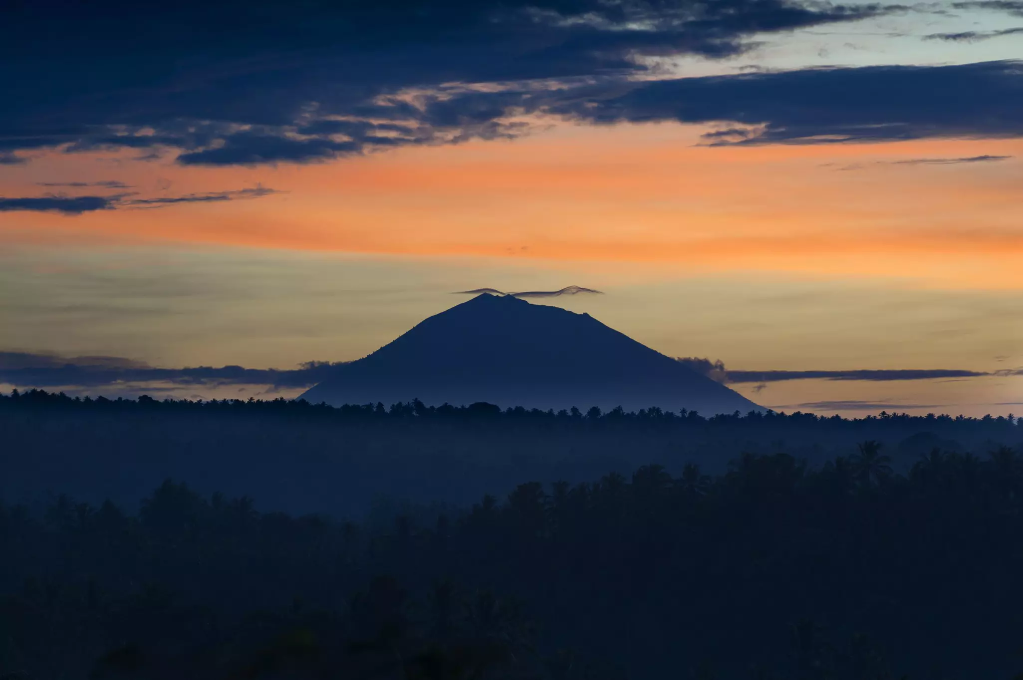 A mountain at sunrise, with a color-streaked sky