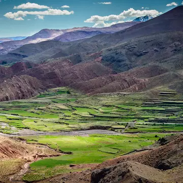 Green fields a valley surrounded by foothills on a sunny day.