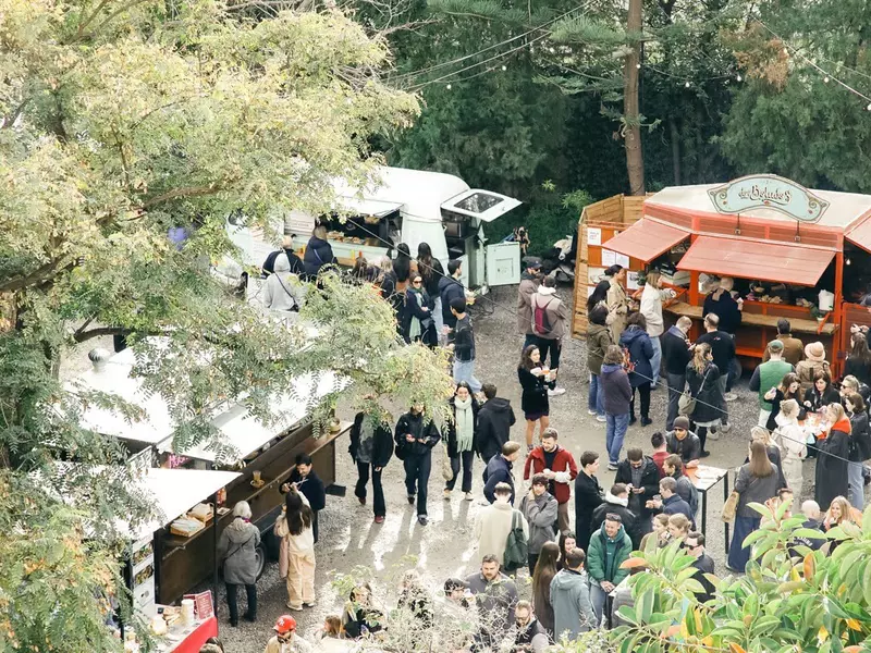 People dine at food trucks at an outdoor market