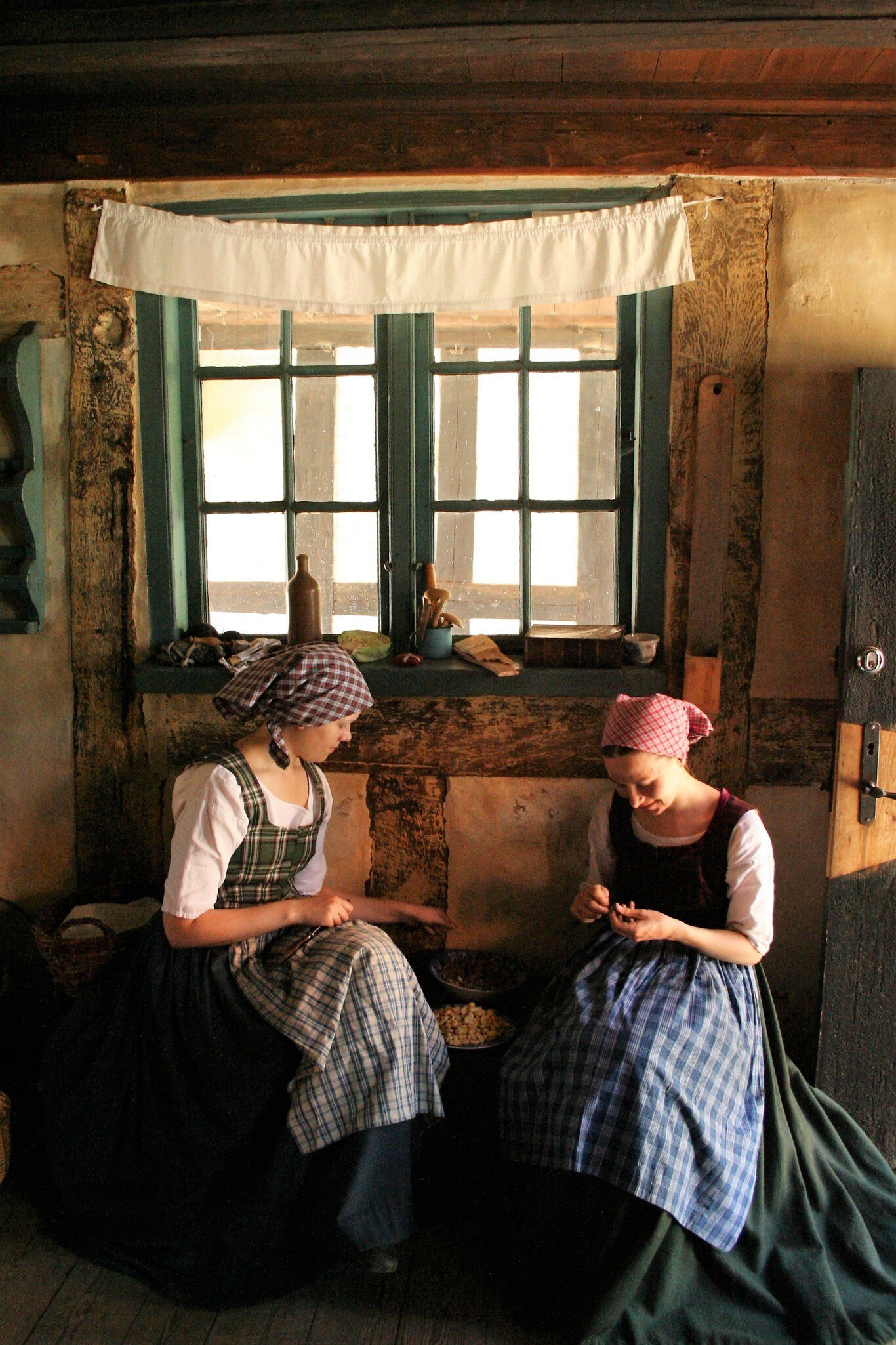 Two girls sewing in traditional clothes at Den Gamle By in Aarhus, Denmark.