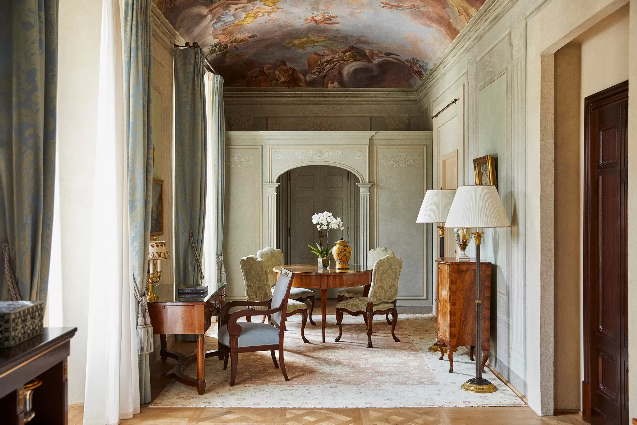 A room with old wood furnishings, including a chair, desk and tall lamps.