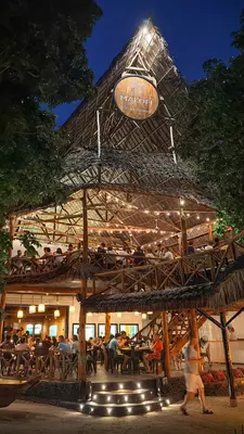 Diners at tables in a restaurant with an open terrace and a balcony.