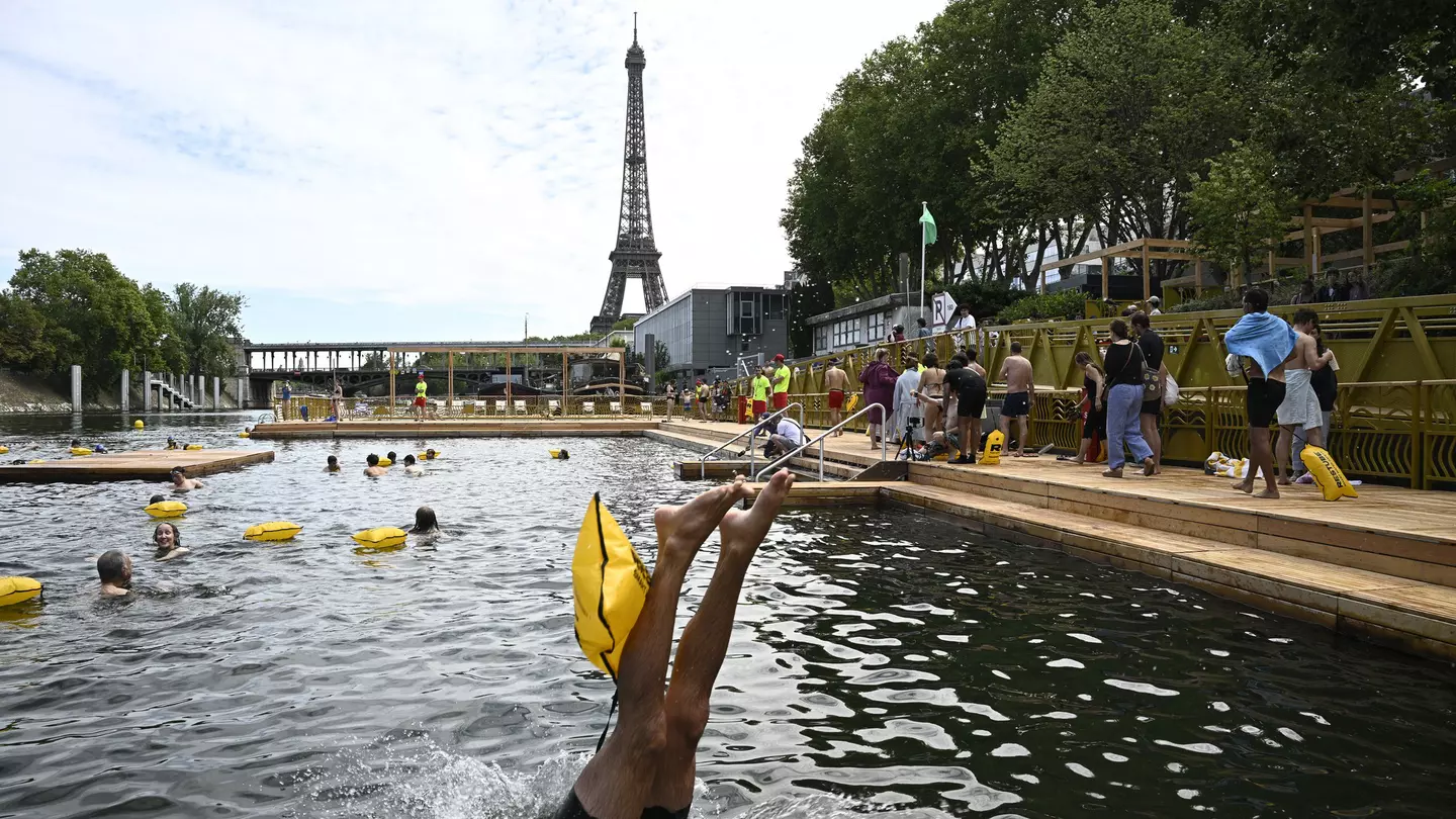 A swimmer dives in the water at the Grenelle safe bathing site on the Seine river on its opening day, in front of the Eiffel Tower in Paris on July 5, 2025