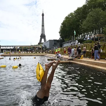 A swimmer dives in the water at the Grenelle safe bathing site on the Seine river on its opening day, in front of the Eiffel Tower in Paris on July 5, 2025