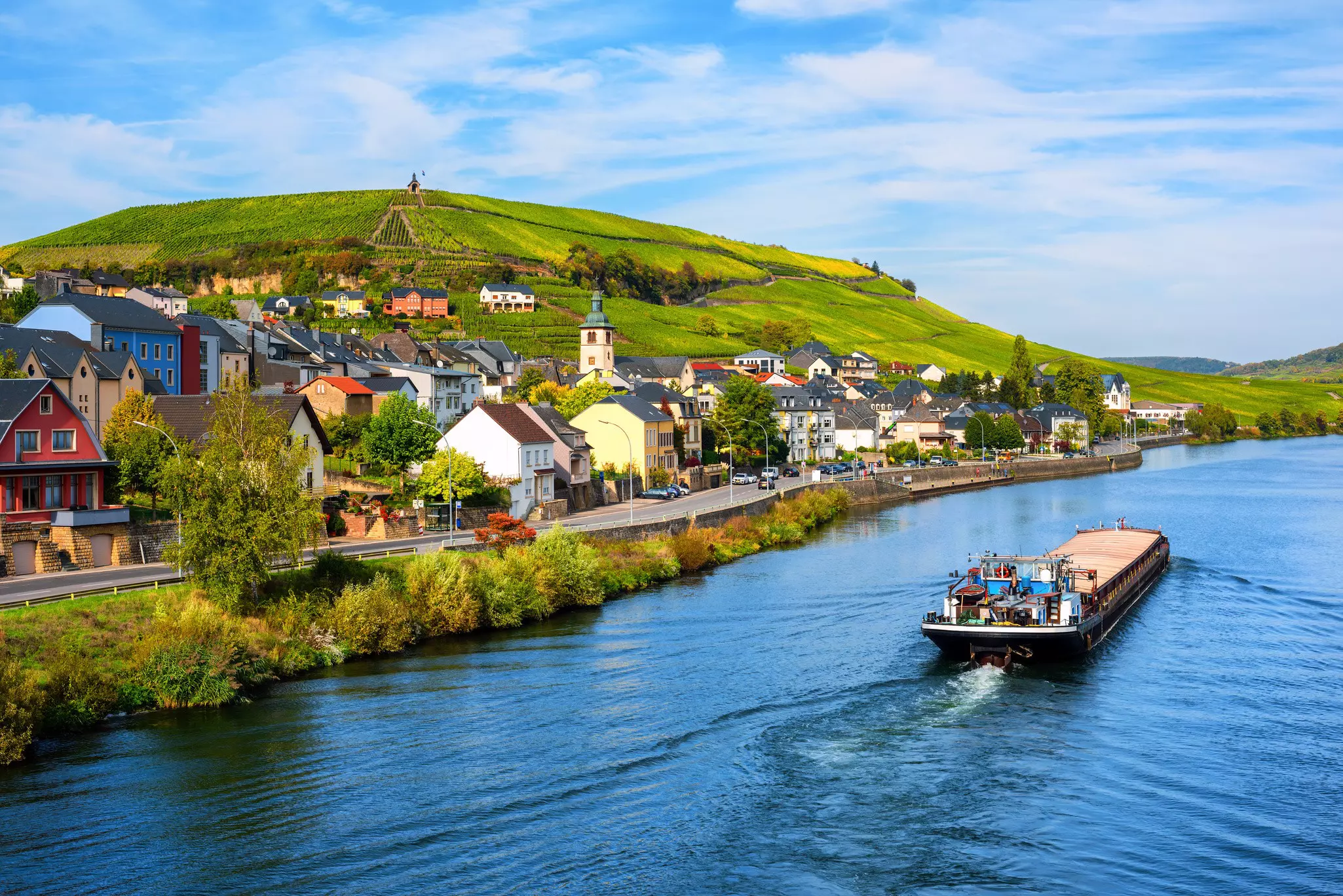 A barge passes vineyards along the Moselle River in Wormeldange, Luxembourg.