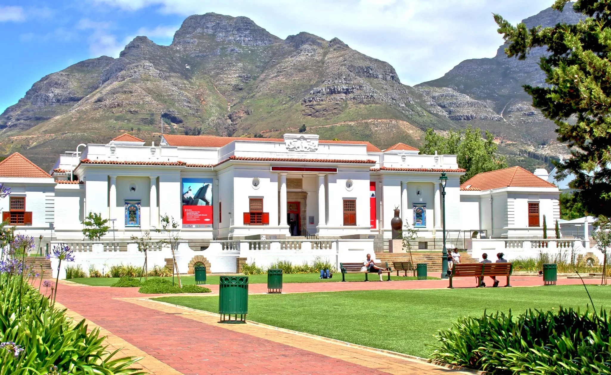 South African National Gallery in Company's Garden, with people seated on benches and mountains in the background