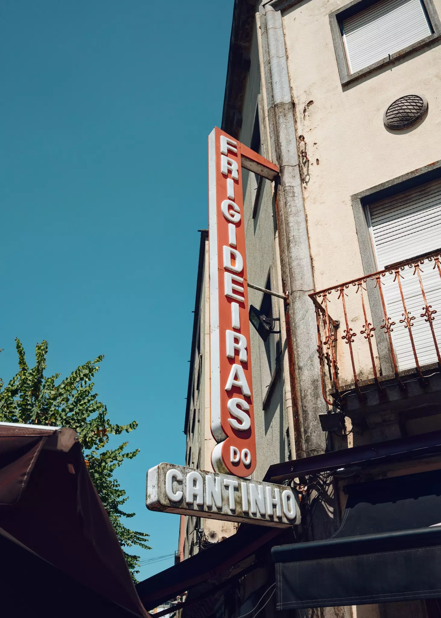 A vintage sign for a restaurant is mounted on the corner of a building in Braga, Portugal.