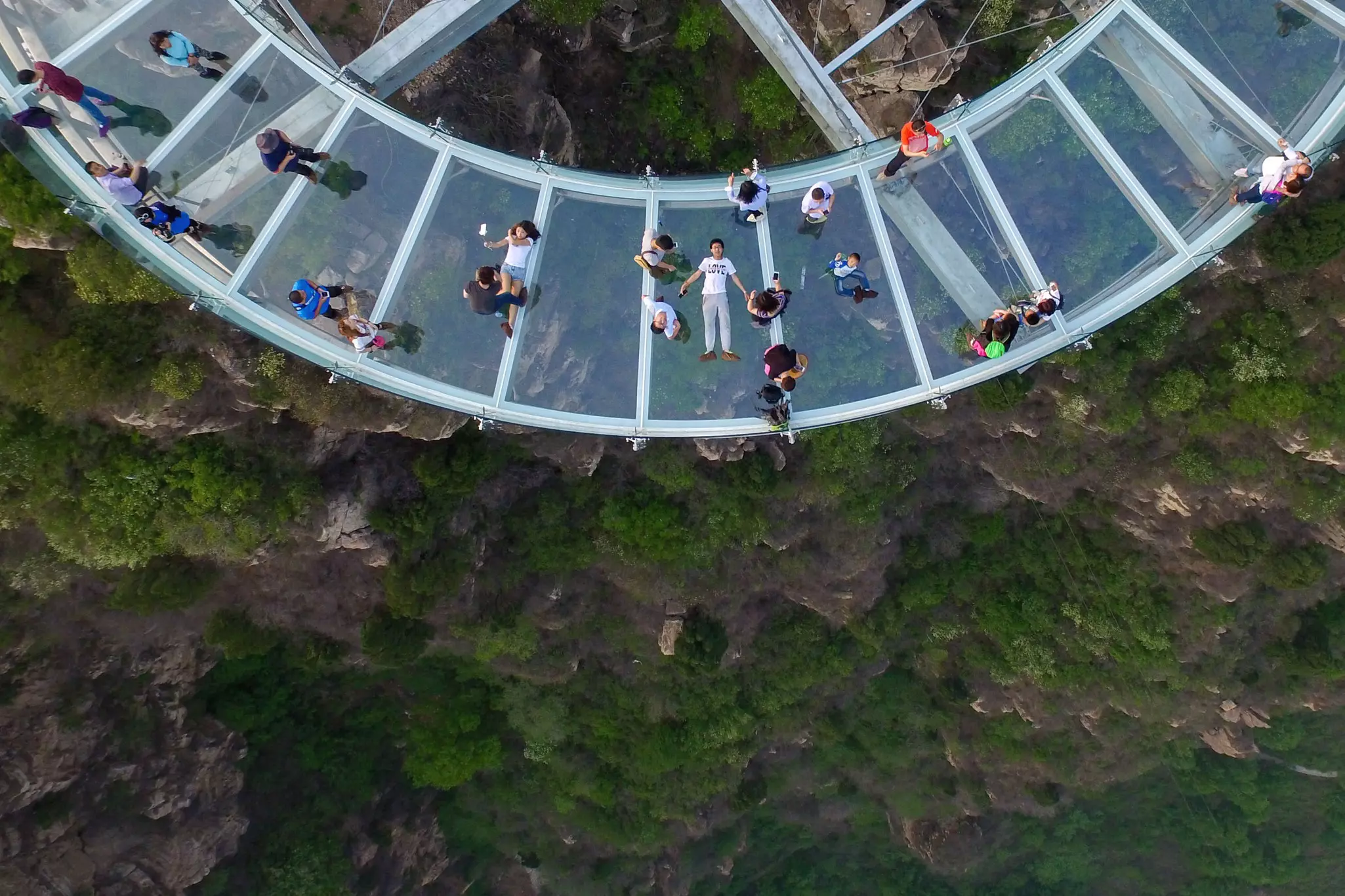 Visitors balanced above a vertiginous drop on the glass sightseeing platform in Shilinxia near Beijing, China.