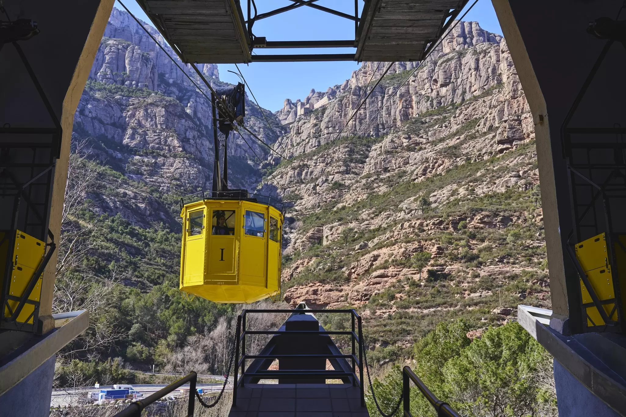 View of a yellow cable car arriving at the station in Montserrat near Barcelona, Spain.