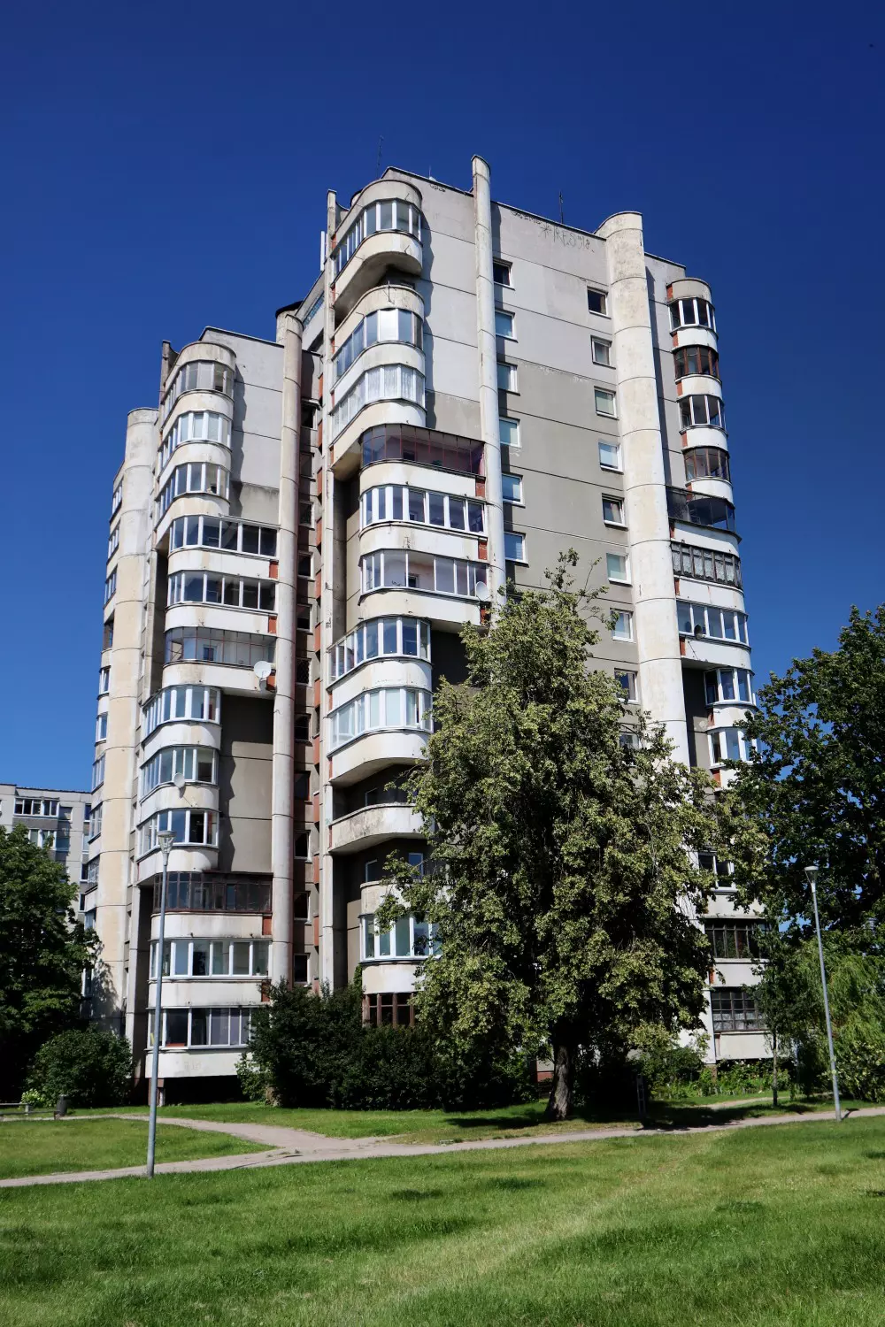 An 11-floor Soviet-style apartment block surrounded by a grass lawn.
