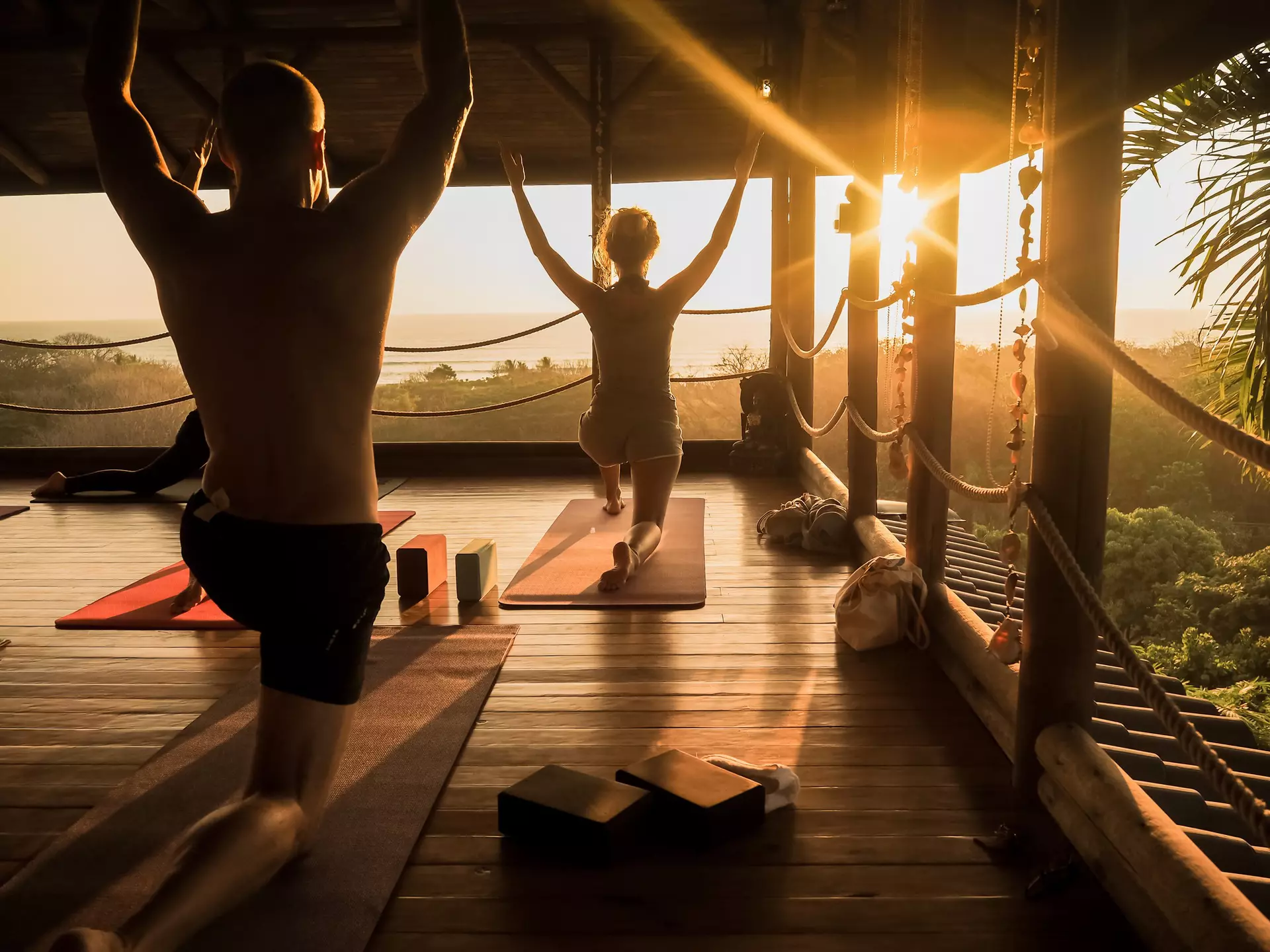 People practice yoga in an open yoga studio near the ocean in Costa Rica while the sun sets..