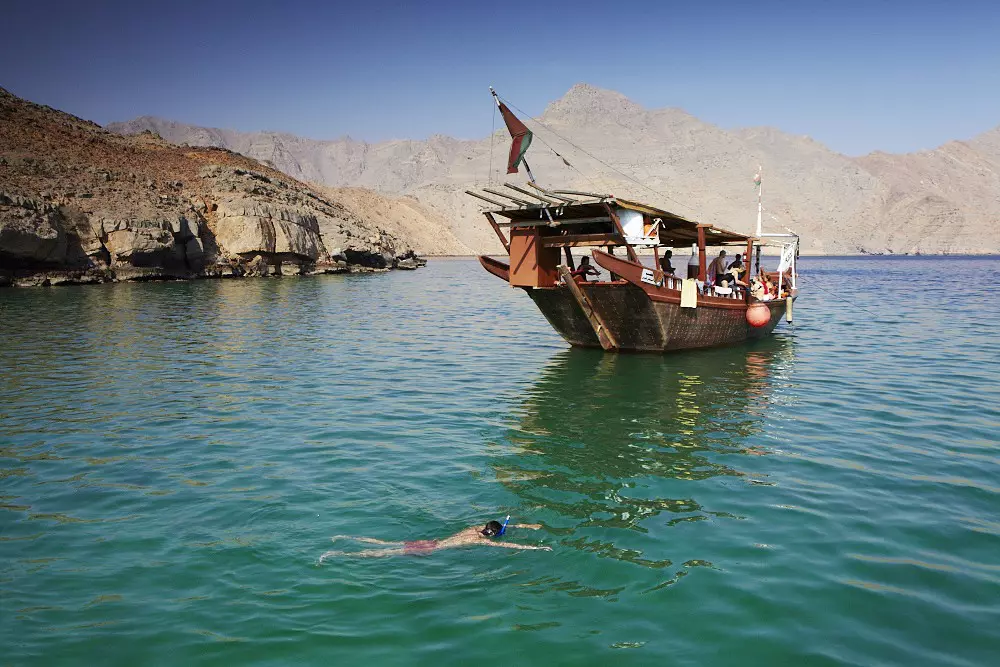 A man snorkels near a traditional boat in the waters off Musandam, Oman