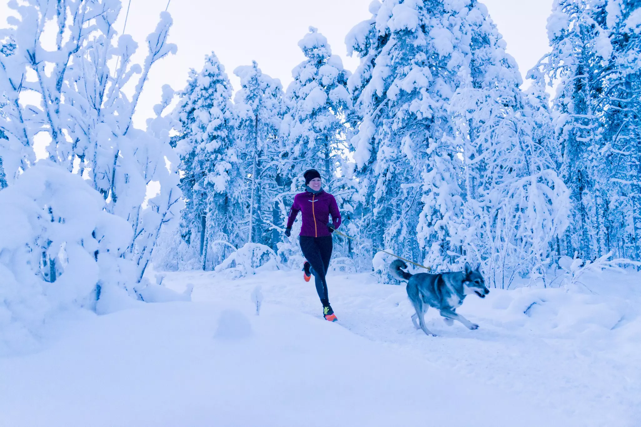 A woman running with her dog in the snow in Sweden