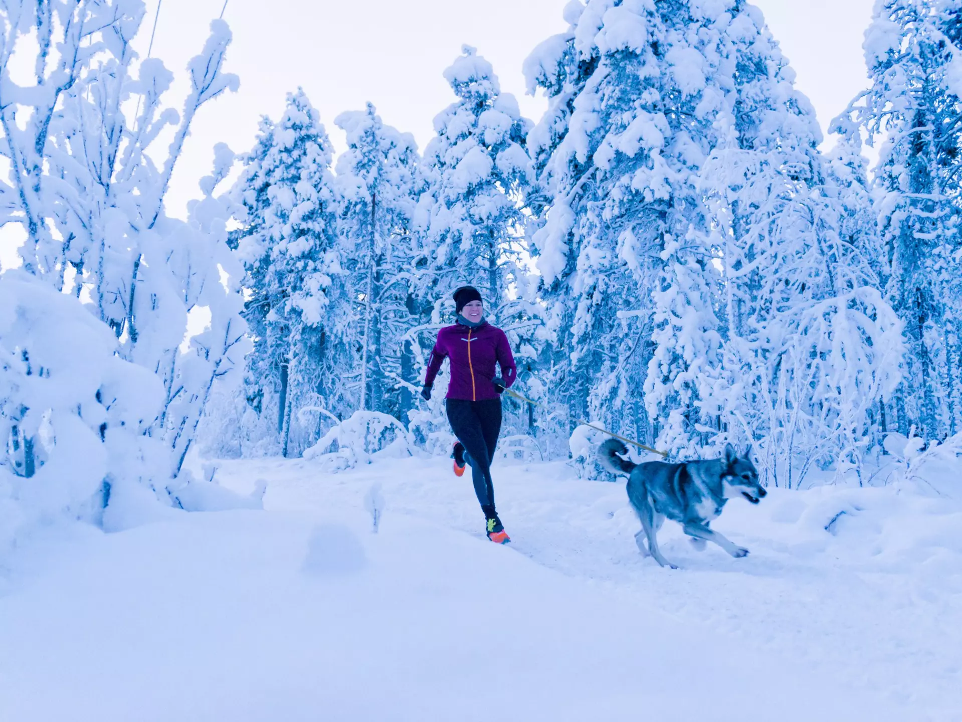 A woman running with her dog in the snow in Sweden