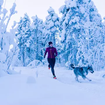 A woman running with her dog in the snow in Sweden