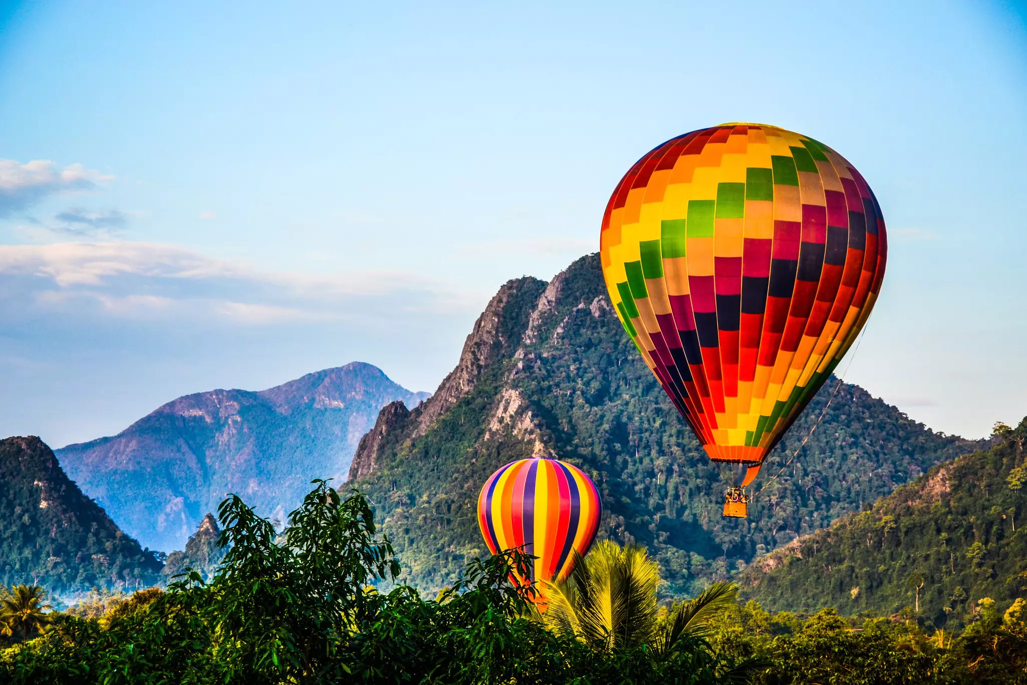 Balloon tour of the mountains in Vang Vieng, Laos, with two large, brightly colored balloons
