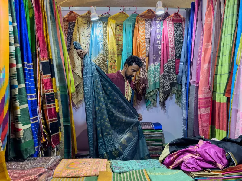 A sari vendor folds saris in his stall. 
