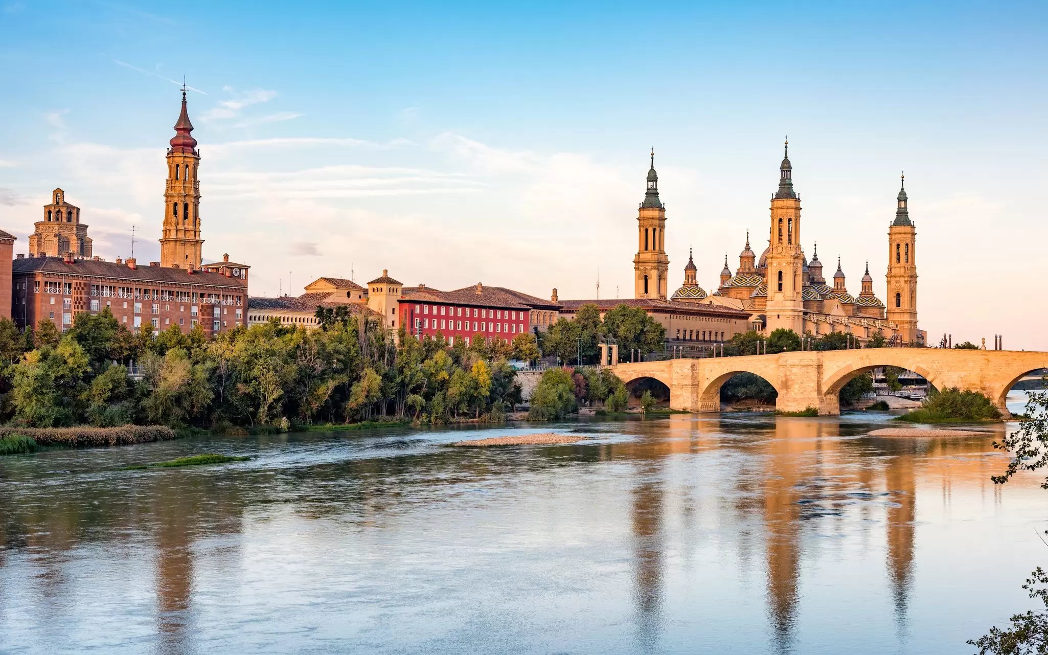 The spires of the Basílica de Nuestra Señora del Pilar reflected in the river in Zaragoza, Spain.
