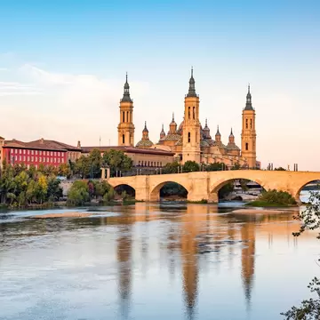 The spires of the Basílica de Nuestra Señora del Pilar reflected in the river in Zaragoza, Spain.