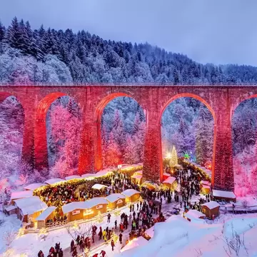 Christmas market in the Ravenna Gorge in the snowy Black Forest, the railway viaduct of the Hoellentalbahn is colourfully illuminated, Black Forest, Breitnau, Baden-Wuerttemberg, Germany
