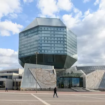 Glass rhombicuboctahedron of Minsk's National Library above gold-etched entrance wings and a wide plaza with a few walkers
