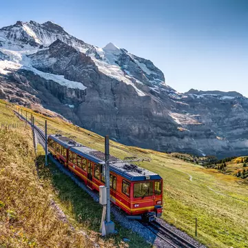 A red train on the Jungfrau railway with the Jungfrau peak behind, Switzerland