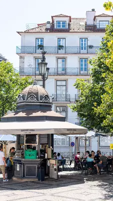 People with drinks sat at tables outside a small kiosk