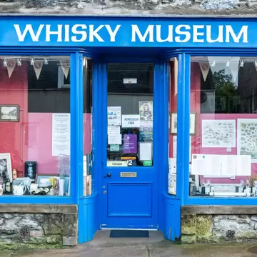 Blue-painted shopfront with WHISKY MUSEUM lettering and bottles in the window