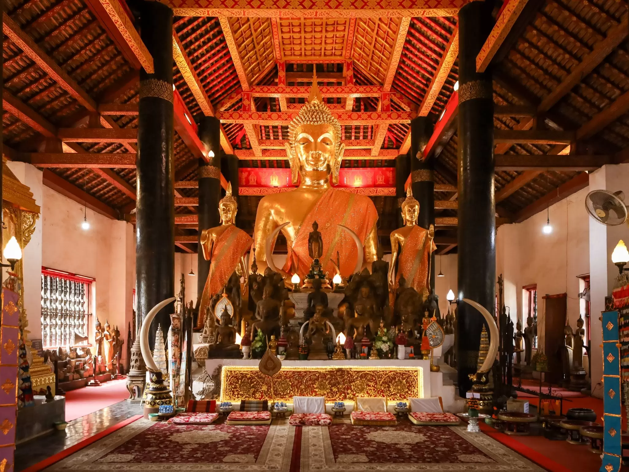 A temple with a golden Buddha statue in the center and smaller statues in front.