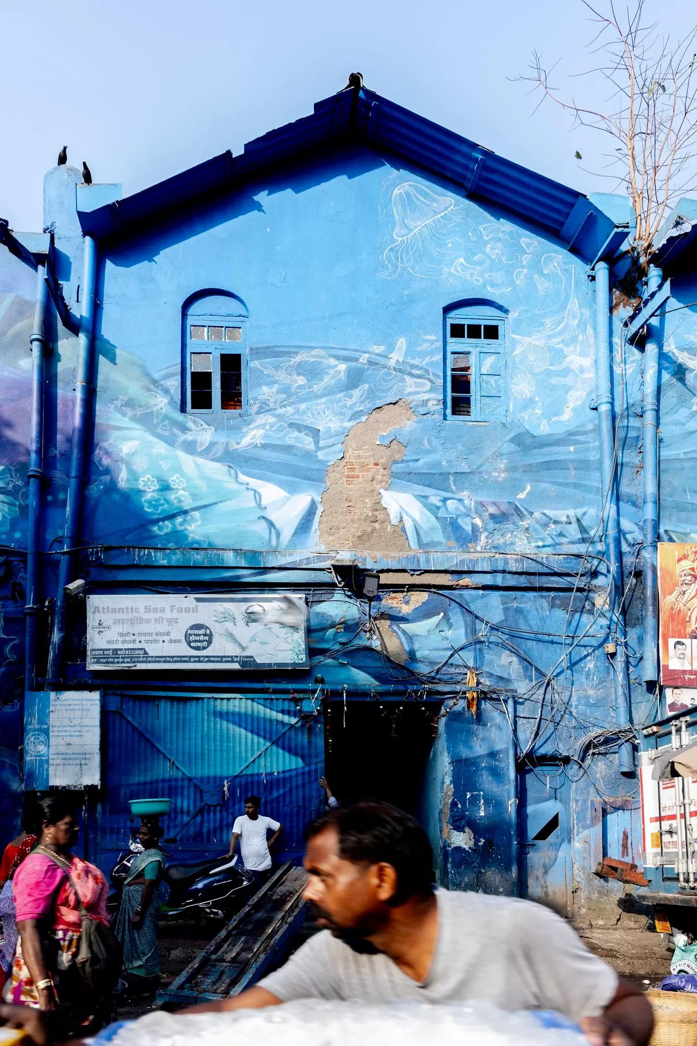 A dilapidated building with a blue mural at the Sassoon Docks fish market, Mumbai