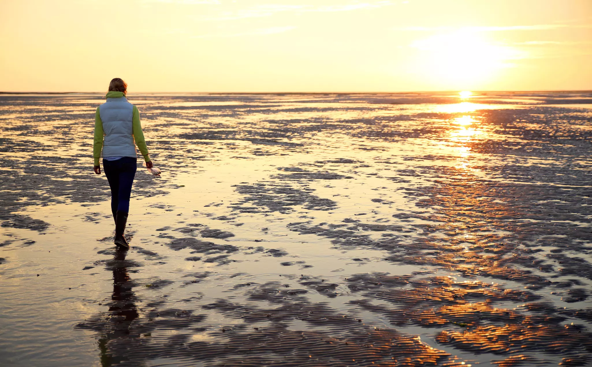 A young woman walks across the mudflats of the Wadden Sea at low tide