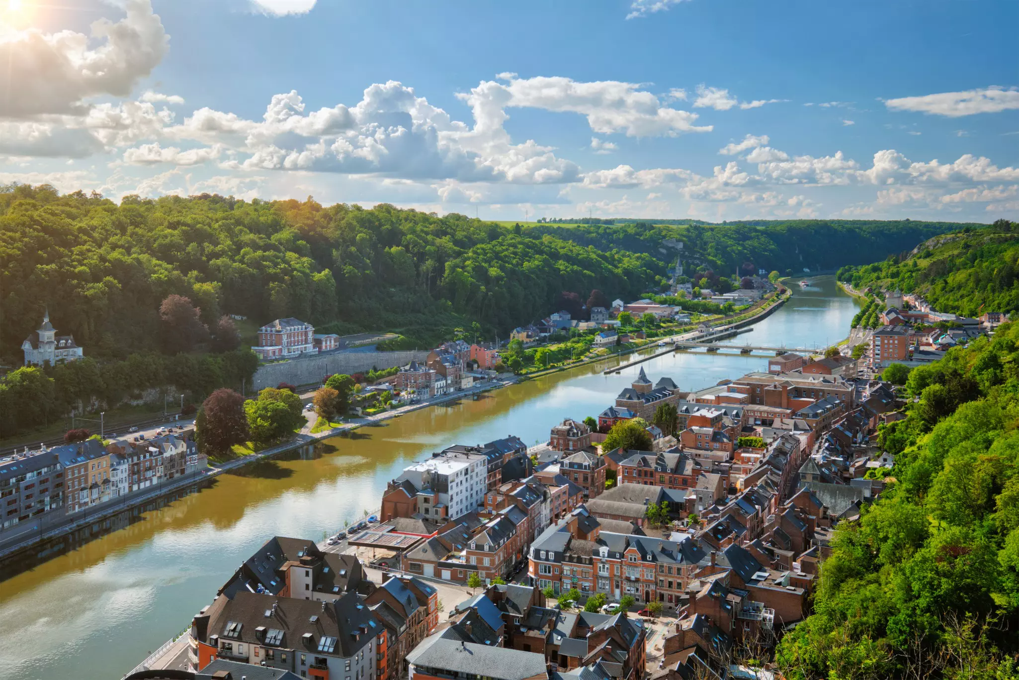A river flows through a town on a summer's day with trees in full bloom.