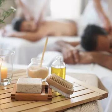A man and woman enjoy a luxurious massage in a white-walled spa.