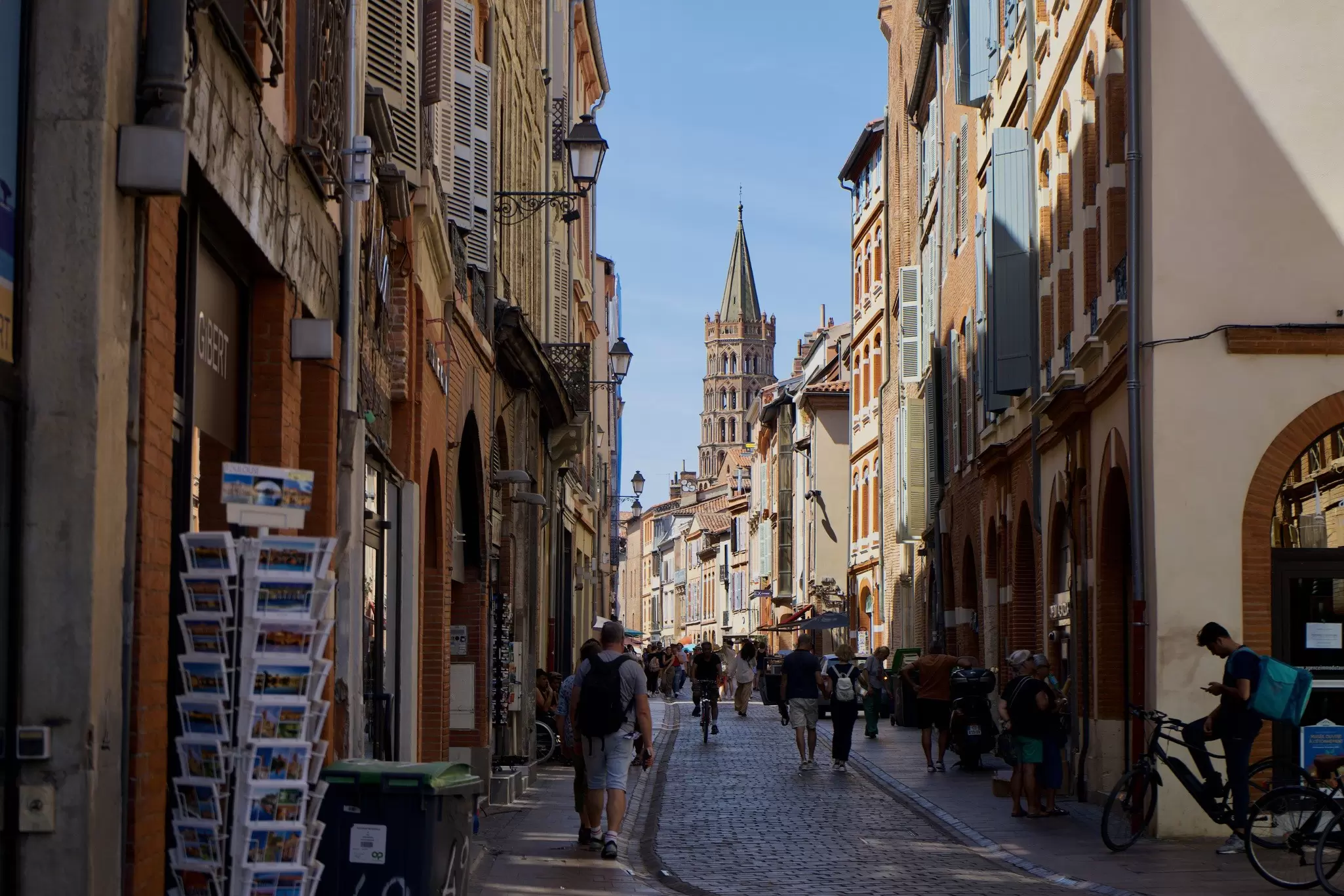 A narrow pedestrianized street leading to a church with a tall pointed spire